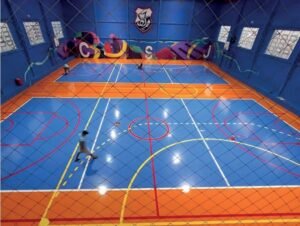 Quadra do ginásio poliesportivo do Colégio São José pintada em azul e laranja com o brasão na parede