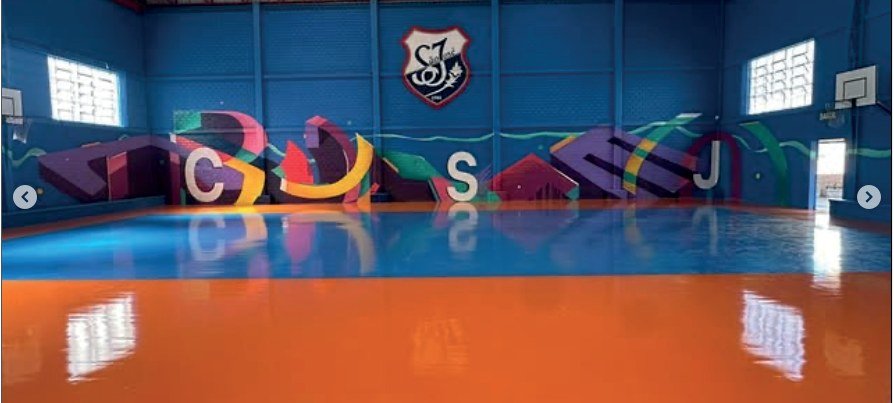 Parede do ginásio do Colégio São José com letreiro grafitado em tons de roxo e azul
