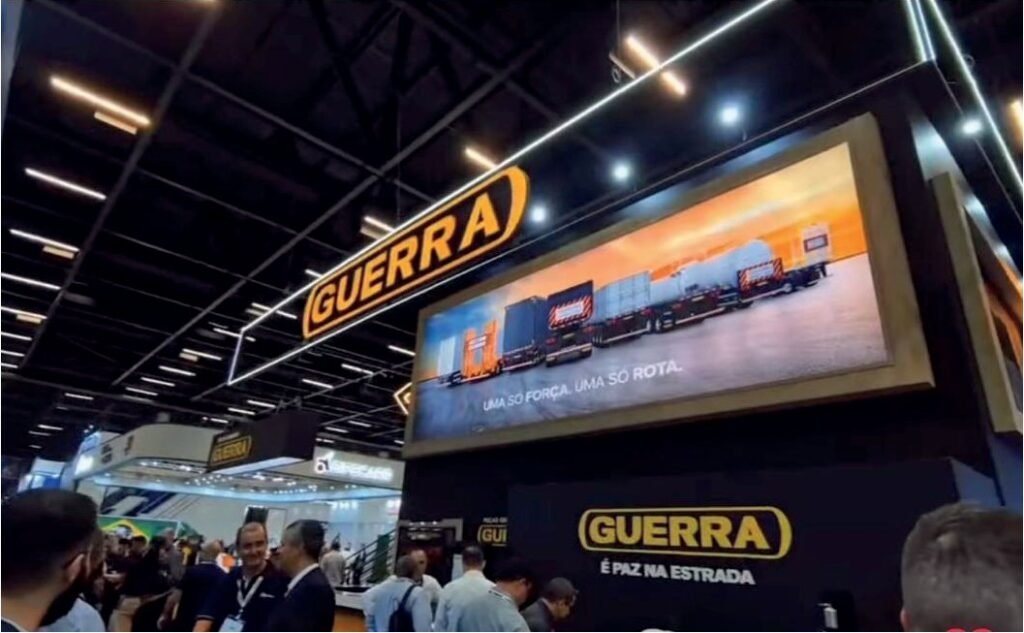 Estande da Guerra na Fenatran 2024 com o letreiro da marca e visitantes circulando