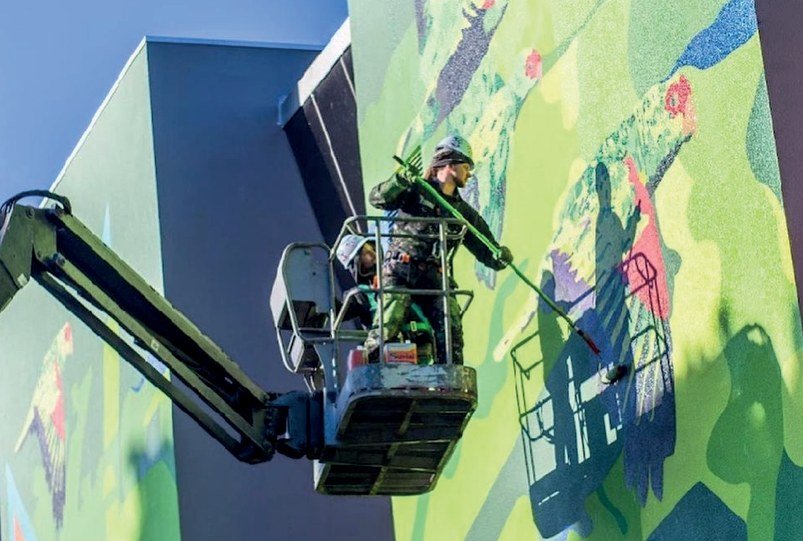 Gustavo Gomes pintando a fachada do IHVET de dentro de uma plataforma elevatória