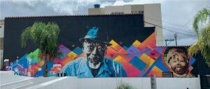 Paredão da sede do Ministério Público Federal coberto por grafite geométrico colorido, com um rosto ao centro