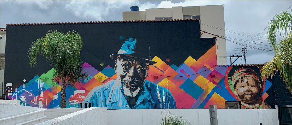 Paredão da sede do Ministério Público Federal coberto por grafite geométrico colorido, com um rosto ao centro