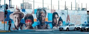 Mural da 11ª Aldeia SESC na EPI Imigrante, com retratos de pessoas de diferentes etnias lado a lado