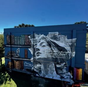 Mural Humanidade pelas Letras na fachada do Bloco F da UCS, em tons de cinza e azul
