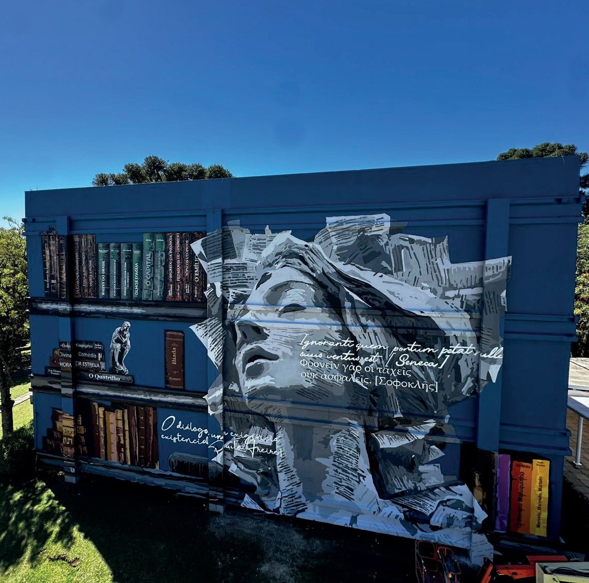Mural Humanidade pelas Letras na fachada do Bloco F da UCS, em tons de cinza e azul