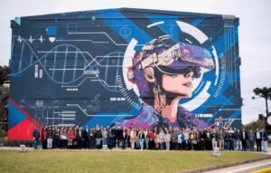Mural do Bloco H da UCS com uma figura de óculos de realidade virtual, e um grupo grande de pessoas posando na frente