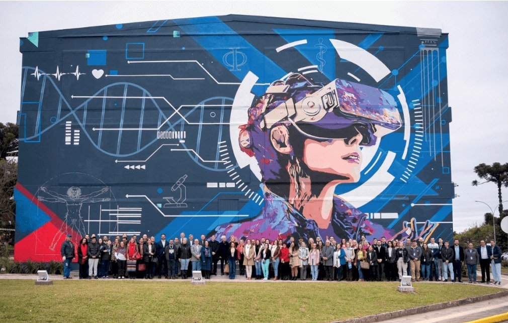 Mural do Bloco H da UCS com uma figura de óculos de realidade virtual, e um grupo grande de pessoas posando na frente