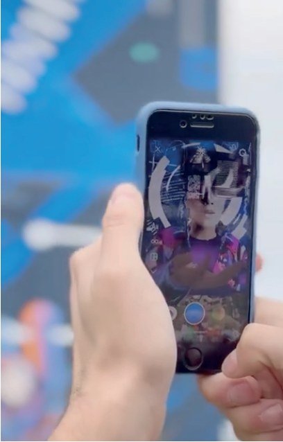 Celular apontado para o mural do Bloco H mostrando a camada de realidade aumentada na tela